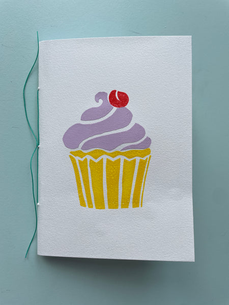 Håndsyet notesbog m. cup cake-tryk, lilla glasur
